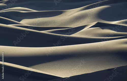 View of the rippled sand dunes at Mesquite Flat Sand Dunes with dramatic shadows and golden hour light in Death Valley, California, United States.