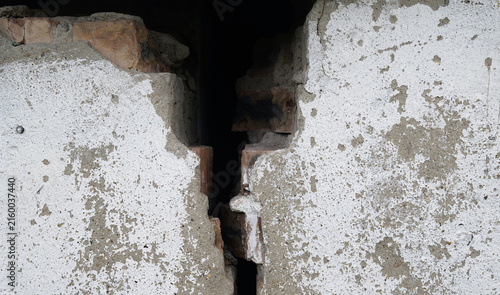 Cracked concrete wall with narrow dark vertical gap.