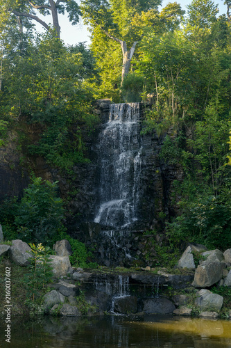Small waterfall surrounded by lush green forest and rocky pool.