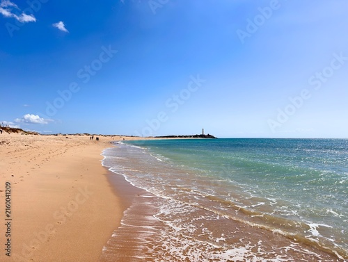 Foto view from the wide sandy beach Playa de las Plumas to the lighthouse Faro de Tra