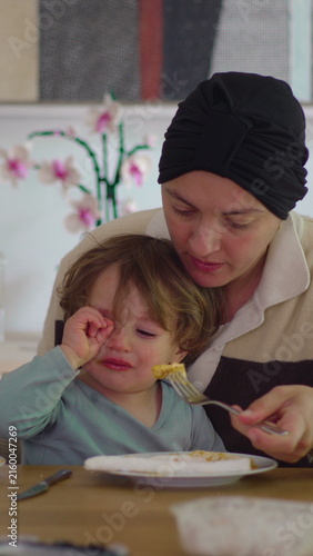 Canvastavla Mother encouraging hesitant toddler during mealtime at home, authentic parenting