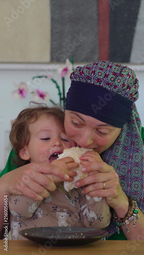 Foto Mother holding toddler close during family mealtime at home, heartwarming parent