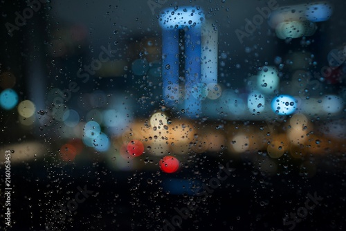 Fotografie ガラスの水滴越しに街の光が滲む静かで印象的な夜の風景  
Raindrops on a window with blurred city lights crea