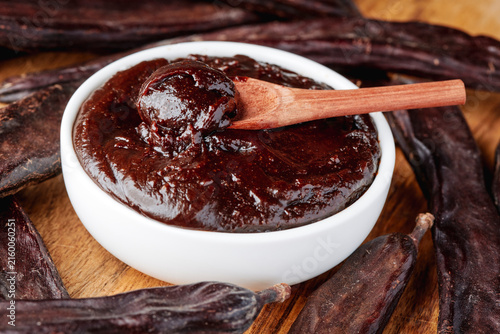 Fotografie thick carob spread surrounded by dried carob pods