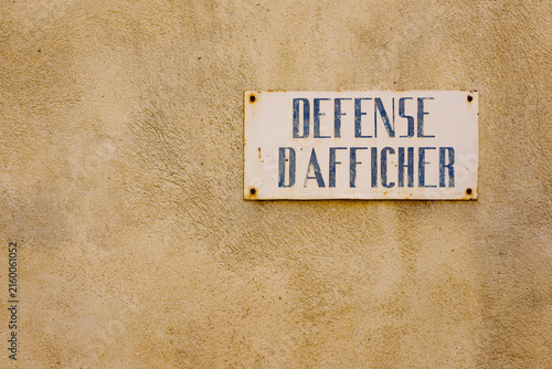 Vintage French no posting sign on weathered ochre wall