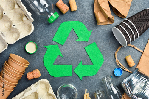 Recycling symbol and various garbage for recycling on gray concrete background. Eco concept.