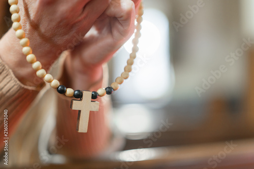 Bild auf Leinwand A woman prays with a rosary inside a European Catholic church during Holy Mass