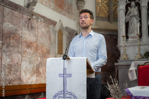 Canvastavla A man stands at a lectern in a European Catholic church reading scripture during Holy Mass