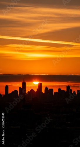 Brilliant orange sky above a dark silhouetted city skyline at sunset