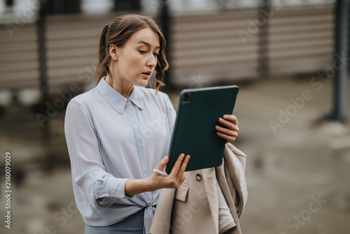 Fotografie A businesswoman looks surprised while reading a tablet during an outdoor moment
