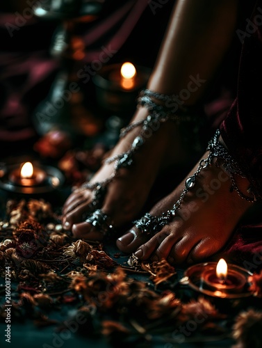 Feet in black chain embellished high heels pose on antique books in candlelight, perfect for fashion editorial, luxury banner