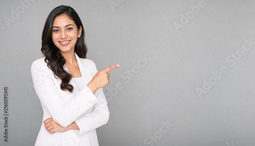 Professional Indian businesswoman pointing to blank space for advertising or presentation in office
