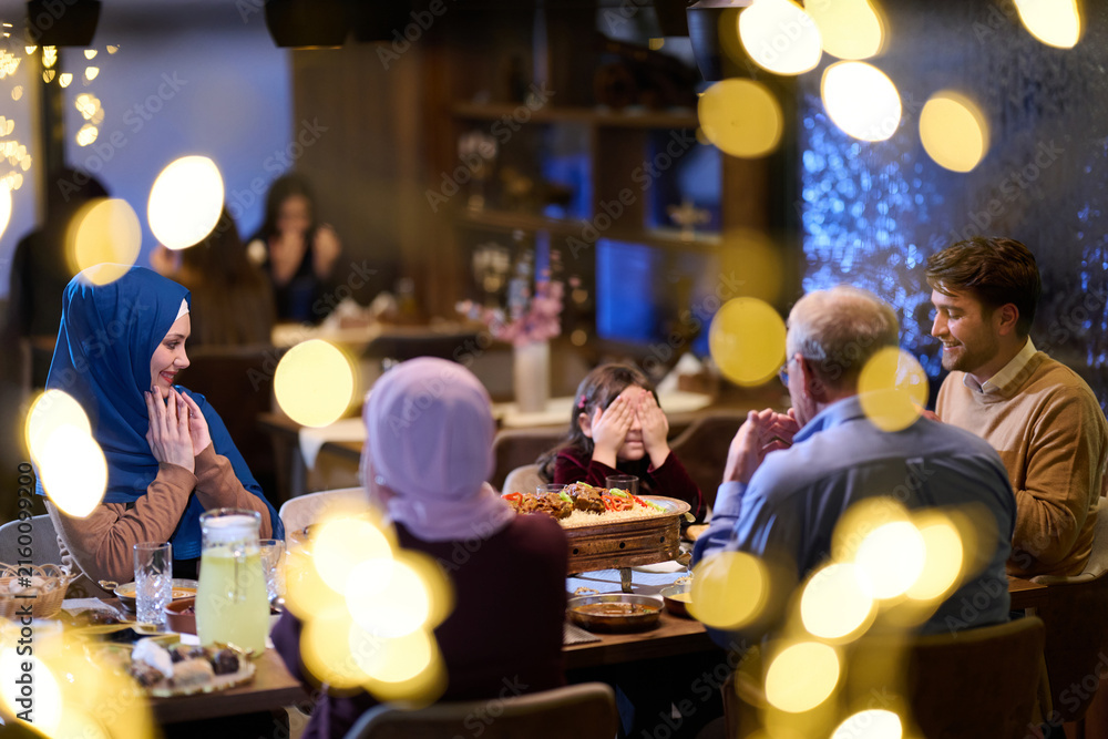 Naklejka premium Muslim Family Dinner Celebration With Multi-Generational Relatives Sharing Joyful Evening Meal