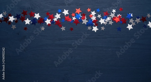 Patriotic red white and blue star confetti on dark wood