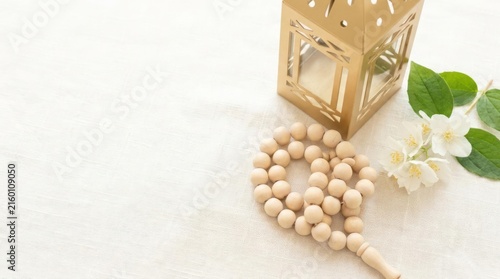 Prayer beads and lantern with flowers on white.