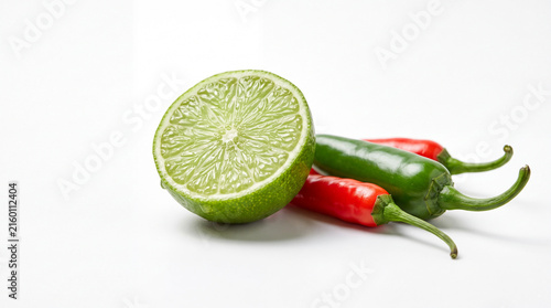 Fresh lime half with red and green chili peppers on white background, vibrant spicy citrus ingredients for cooking, salsa, seasoning and garnish