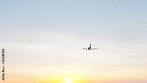 Commercial passenger airplane flying through a warm sunset sky, ideal for aviation, air travel, tourism, transportation, airline, and travel content.