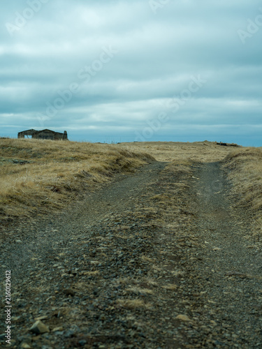 Remote gravel road leading through rural Icelandic landscape
