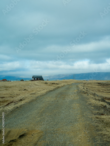 Remote gravel road leading through rural Icelandic landscape
