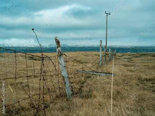 Weathered fence in rural Iceland under dramatic cloudy sky