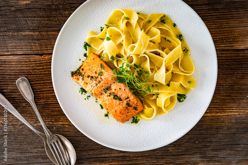 Fototapeta premium Pasta with baked salmon steak on wooden table 