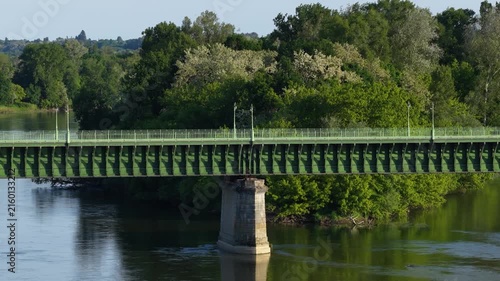 The Pont Canal de Briare, an iconic green metal aqueduct bridge spanning a calm river surrounded by lush green trees and dense forest.