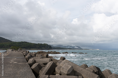 Bild auf Leinwand Concrete Tetrapod Wave Breakers on Japanese Coastline with Ocean Waves and Cloud
