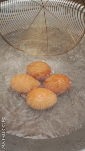 Boiling eggs process. Piercing shells, lowering eggs into boiling water, stirring, cooling in ice water, peeling, and serving soft-boiled eggs with jammy yolks.