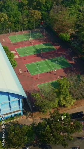 Top down aerial of tennis courts beside covered sports building