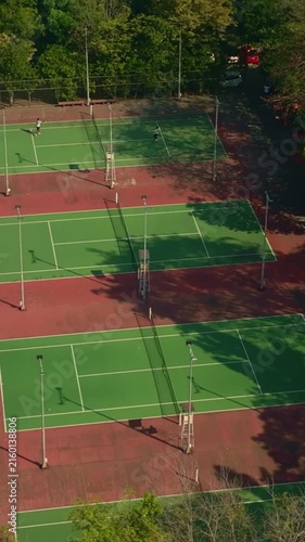 Oblique aerial view of multiple tennis courts beside sports arena