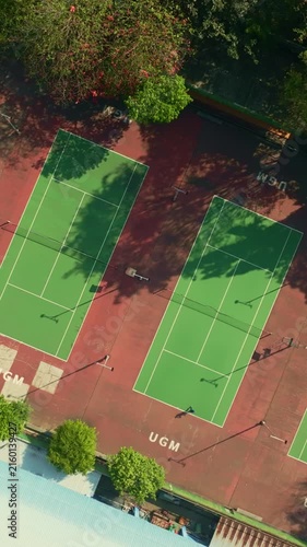 Overhead drone view of green and red tennis courts