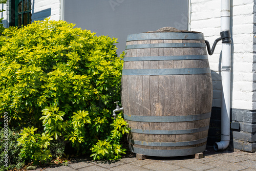 Wooden rainwater collection barrel on modern home exterior for eco friendly rainwater collection, storage and reuse