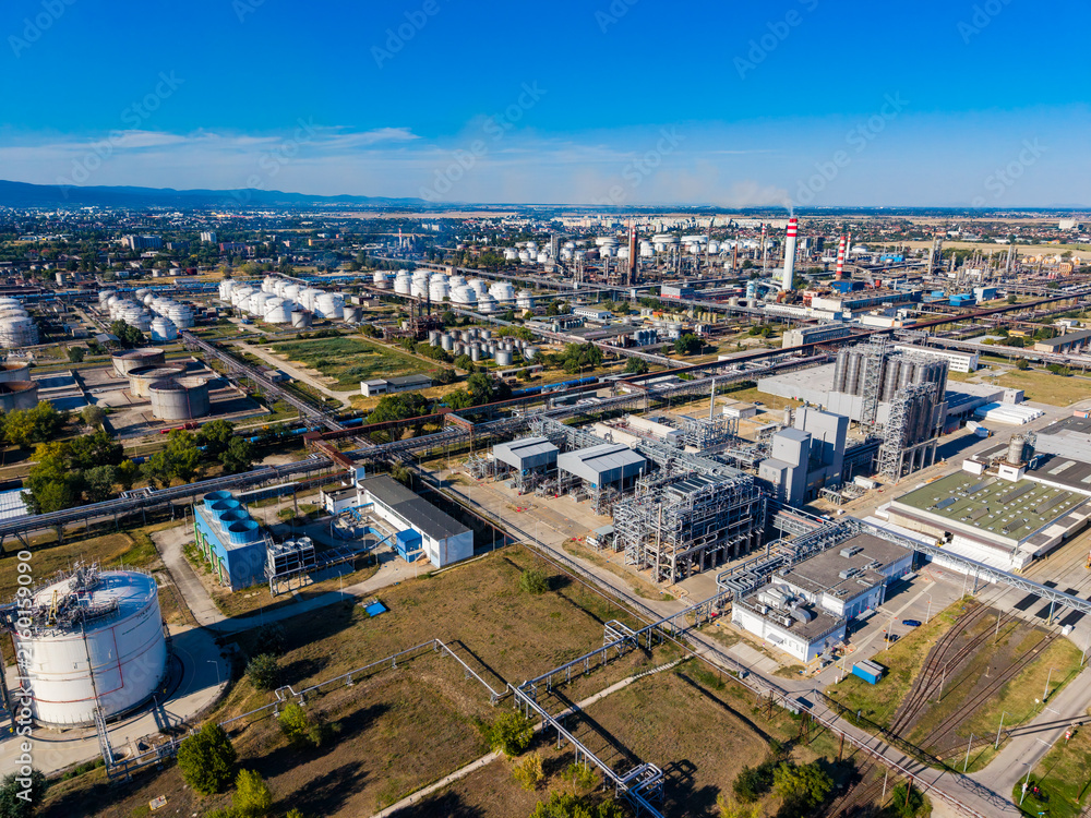 Fototapeta premium View of a large industrial complex in a city with pipelines and storage tanks during daytime