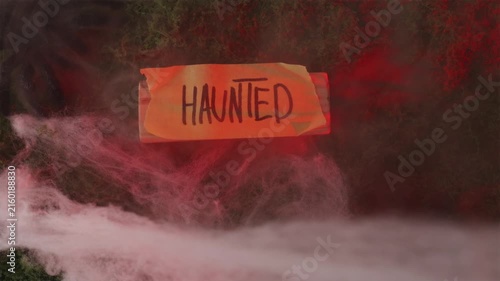Spider shadow crawling over Haunted sign in smoky red light