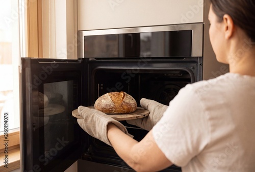 Home baker placing sourdough bread into a modern oven