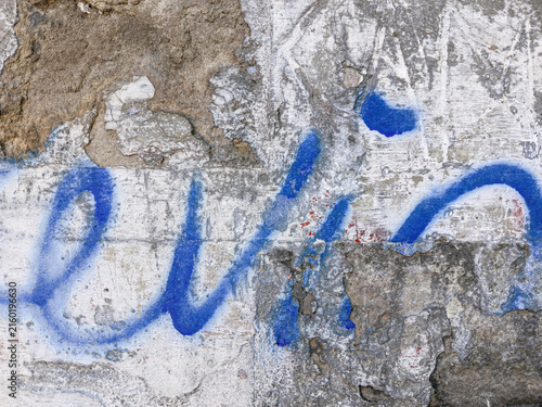 Blue spray paint graffiti on weathered concrete wall urban street art