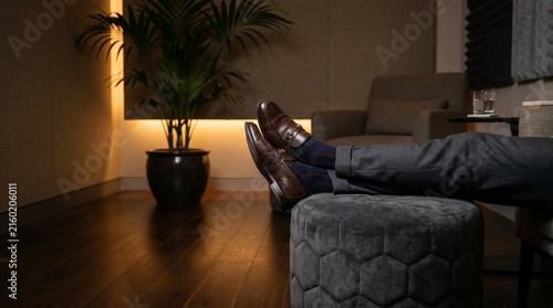 Close Up of Employee Feet on Ottoman in Low Lit Office Decompression Room, Corporate Rest Zone, Modern Workplace Interior Comfort, Lifestyle Photo