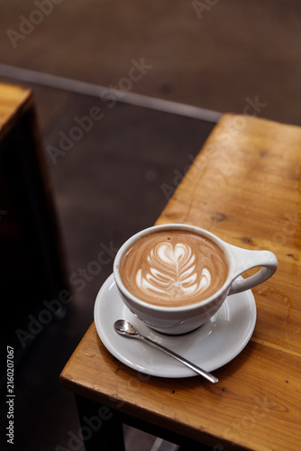 Obraz na plátně Cup of fresh cappuccino with beautiful latte art on a saucer on a wooden table i