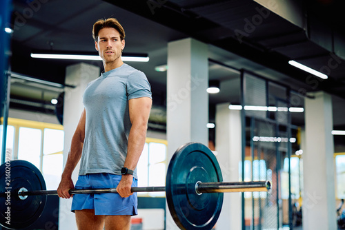 Obraz na płótnie Male athlete holding a heavy barbell, focused on his workout