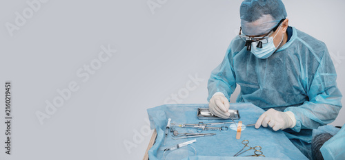 A dental surgeon prepares a connective tissue graft to cover gum recession, thicken the gum, or improve its contour during dental surgery. banner copy space