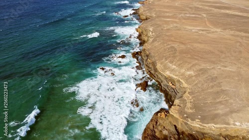 Aerial footage showing a stark contrast between the turquoise ocean and the arid desert coastline