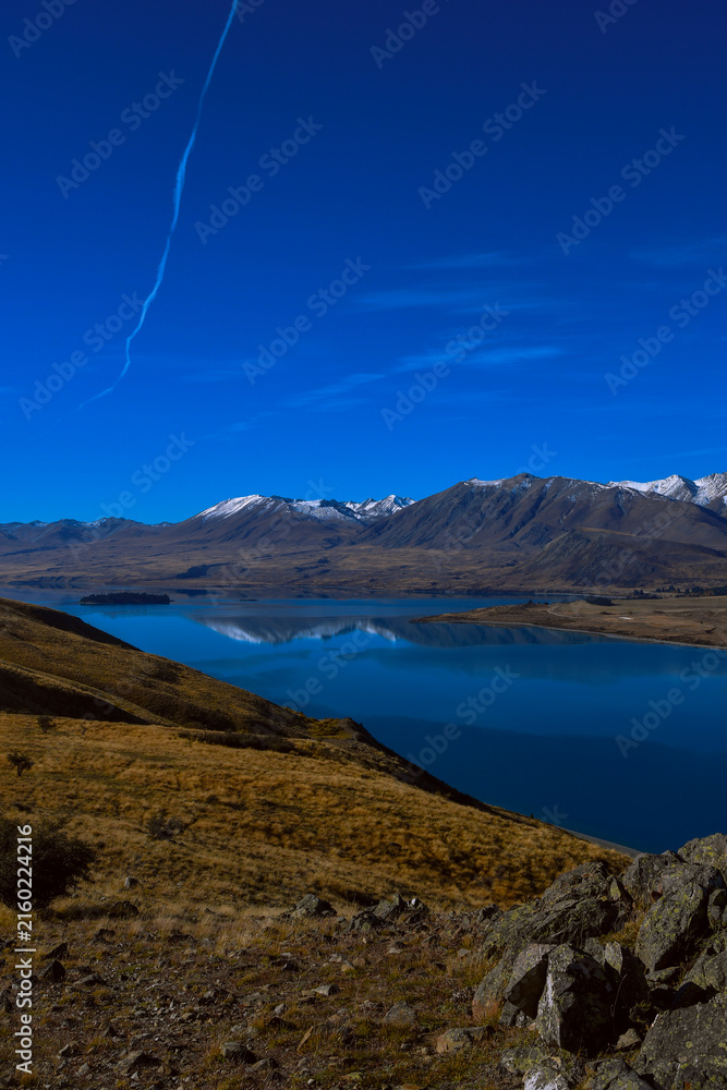 Fototapeta premium Lake Tekapo and snow-capped Southern Alps reflected in calm blue water, New Zealand