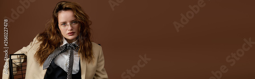 Bild auf Leinwand Stylish young woman showcases elegance in a chic outfit against a warm backdrop