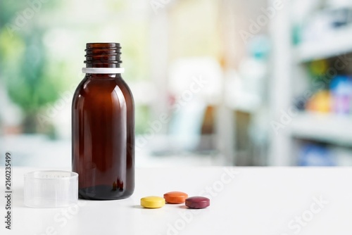 Botella de medicamento con pastillas en una mesa en farmacia