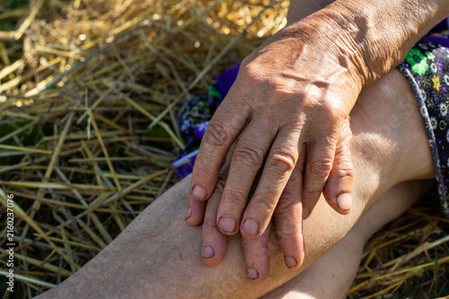 Bild auf Leinwand Close up of wrinkled elderly hands of a senior peasant woman resting on her leg