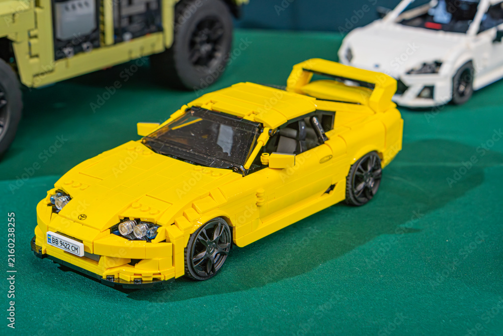 Fototapeta premium Summary Collection of Lego model cars, primarily sports and race cars with some trucks, arranged on a vibrant green surface Prominent yellow LEGO sports car at - Kyiv, Ukraine - June 7, 2025
