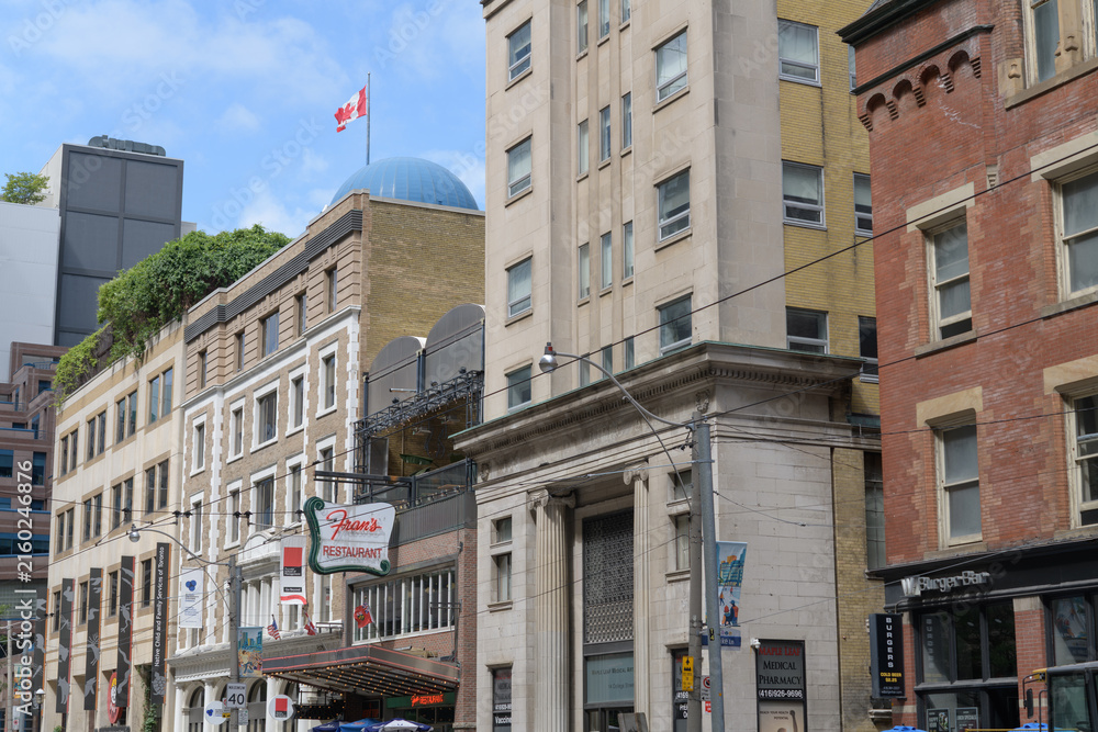 Fototapeta premium perspectival view of College St (north side) from about Yonge St to historic buildings including sign outside Fran's Restaurant located at 20 College St, Toronto
