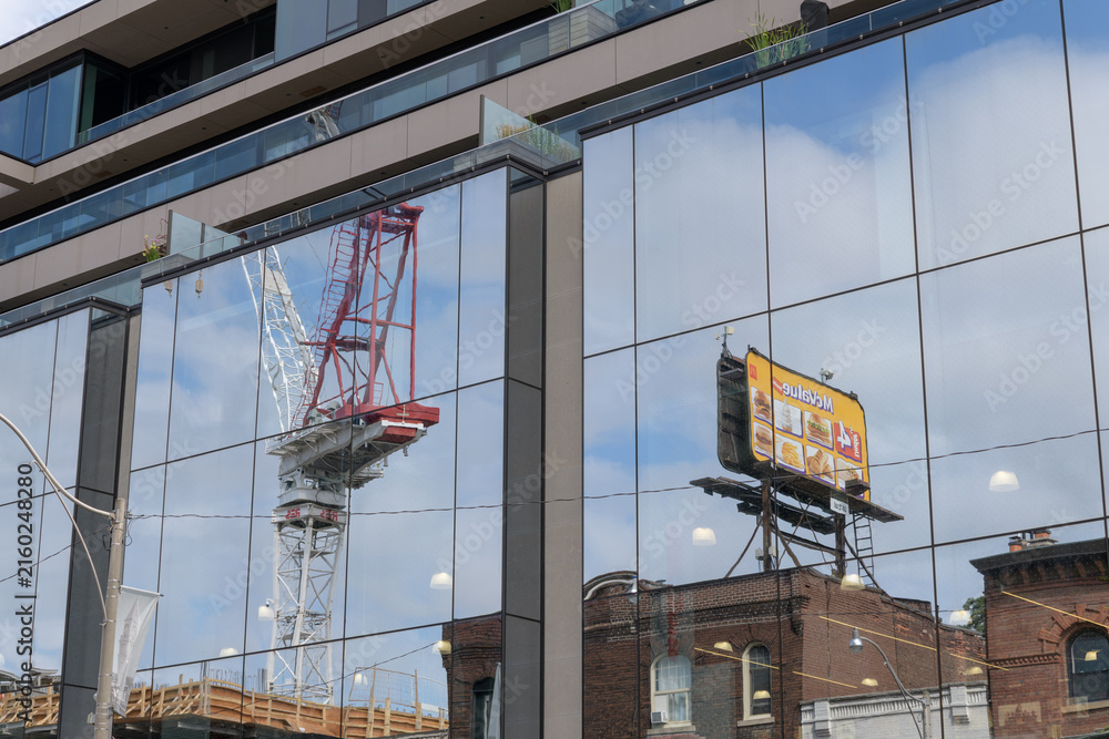 Obraz premium rooftop billboard with McDonald's Canada advertising, and crane at the One Roxborough West development, all reflected off the mirrored windows at 1027 Yonge St, Toronto