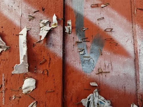 Public wooden bulletin board painted reddish-brown with small scraps of paper and staples