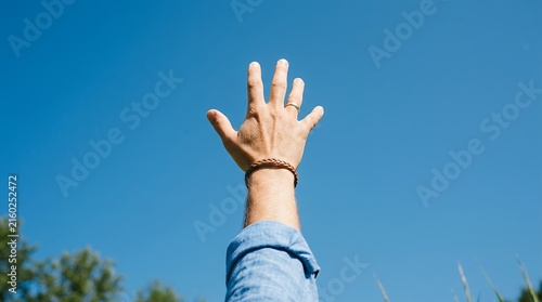 Conceptual view of a human hand stretched upward reaching toward the vast clear blue sky on a bright sunny day hand reaching sky blue clear freedom hope human arm upward dream bright sun sunny